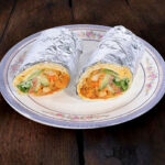 Middle Eastern falafel wrap halves displayed on dark wood